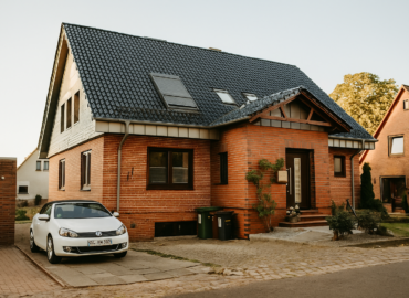 ChatGPT Image Oct 10, 2025, 04_01_44 PM A white Volkswagen electric car is parked beside a modern house with rooftop solar panels, representing a home EV solar charging setup.