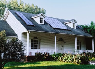 aasing-gwok-zqa6PTWtibs-unsplash Small white house with a black roof surrounded by trees, showcasing a cozy residential property suitable for solar panel installation in Minnesota.