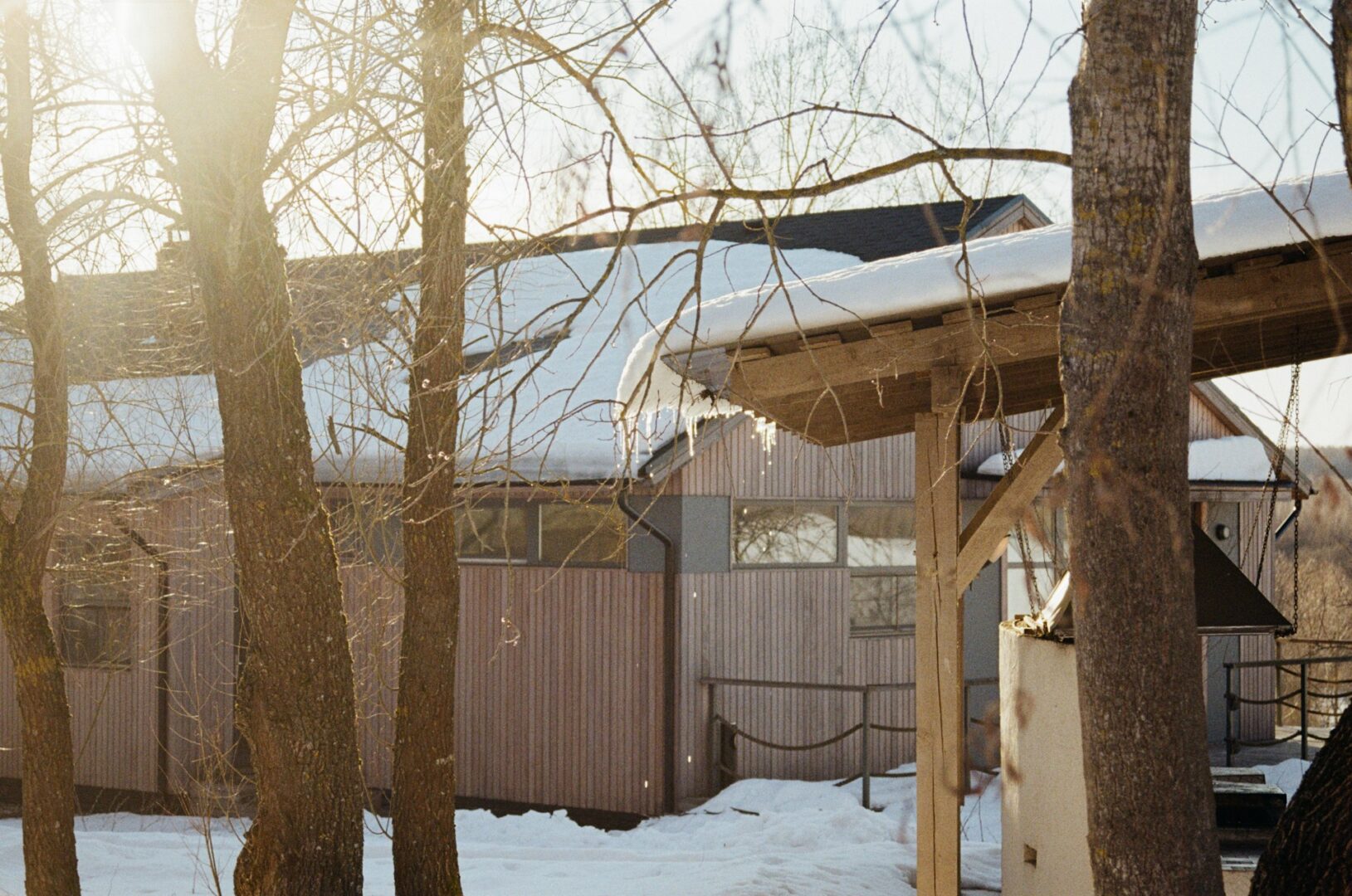 How a Solar Roofing Company Designs Panels to Withstand Snow and Harsh Winters 1 A snow-covered house nestled in a snowy forest clearing under a grey winter sky