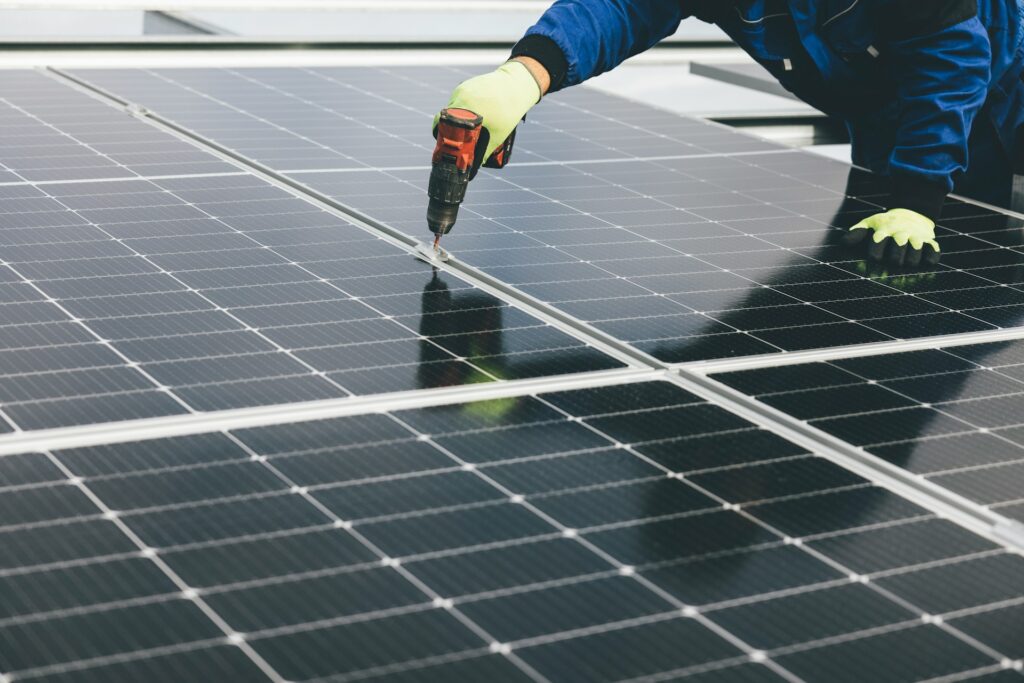 Technician installing solar panels on a rooftop by a commercial solar company in Minnesota.