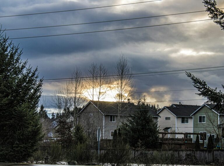 peter-robbins-8whEpio29X4-unsplash Sunlight breaking through clouds over suburban houses in Minnesota, illustrating how solar panels can still generate energy on cloudy days.