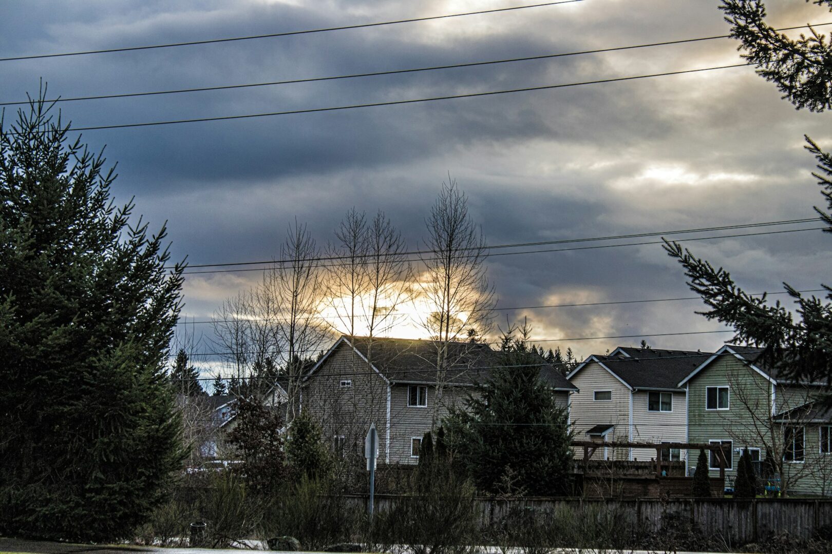 Sunlight breaking through clouds over suburban houses in Minnesota, illustrating how solar panels can still generate energy on cloudy days.