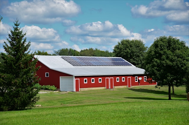 A large red barn surrounded by green fields under a clear blue sky, representing sustainable farming and renewable energy potential in rural Minnesota.