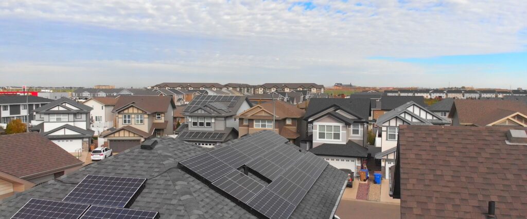 Row of modern houses with solar panels installed on their roofs under clear blue sky, showcasing sustainable residential energy solutions.