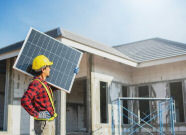 siwawut-phoophinyo-S2Jxs3DXpyA-unsplash A man holding a solar panel in front of a house, representing residential solar energy installation and sustainable power solutions in Saint Paul.