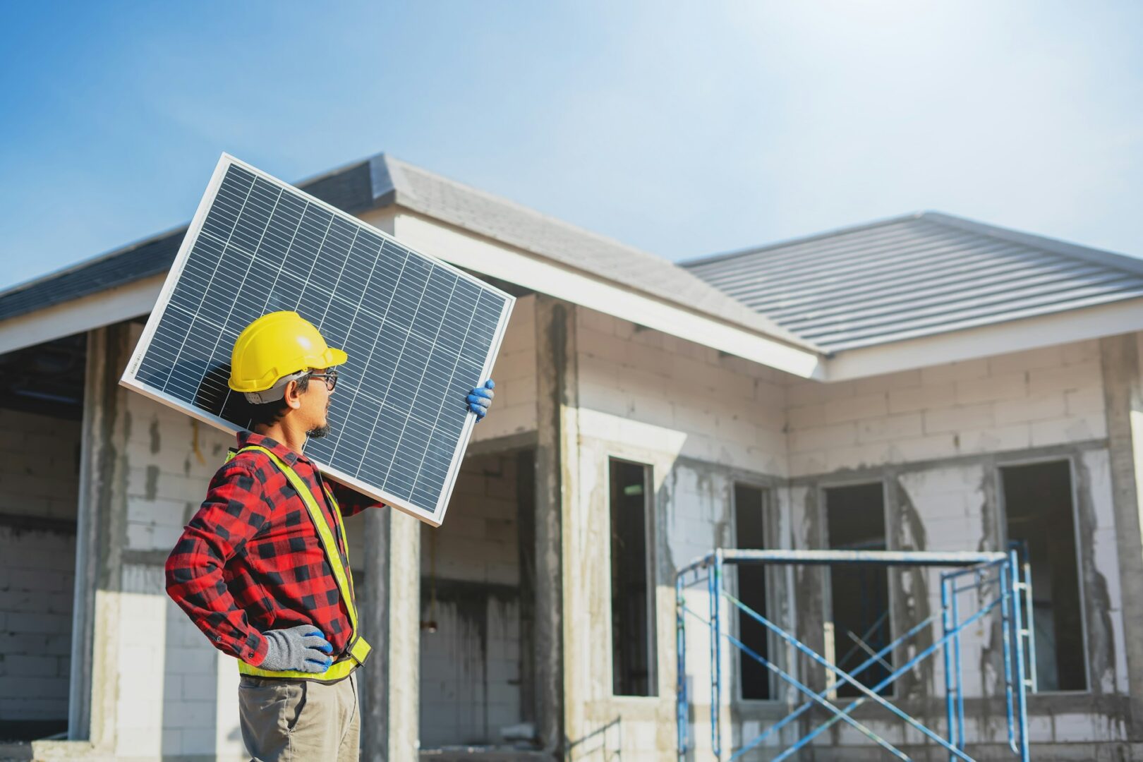 A man holding a solar panel in front of a house, representing residential solar energy installation and sustainable power solutions in Saint Paul.