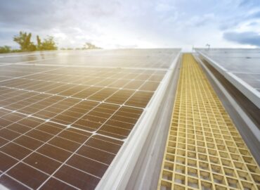 Home with rooftop solar panels and a battery storage unit, representing energy independence and cost savings with modern solar battery storage.